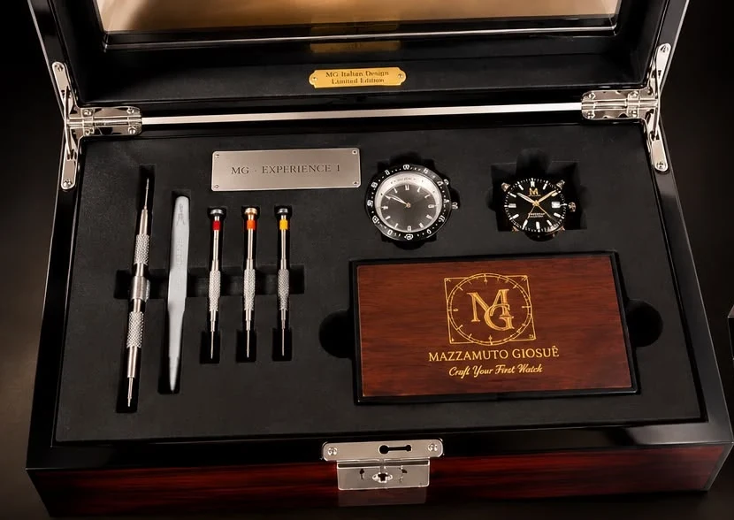 Le coffret ouvert vu de face : les outils alignés dans la mousse noire, les deux montres et la plaque en bois au monogramme MG.